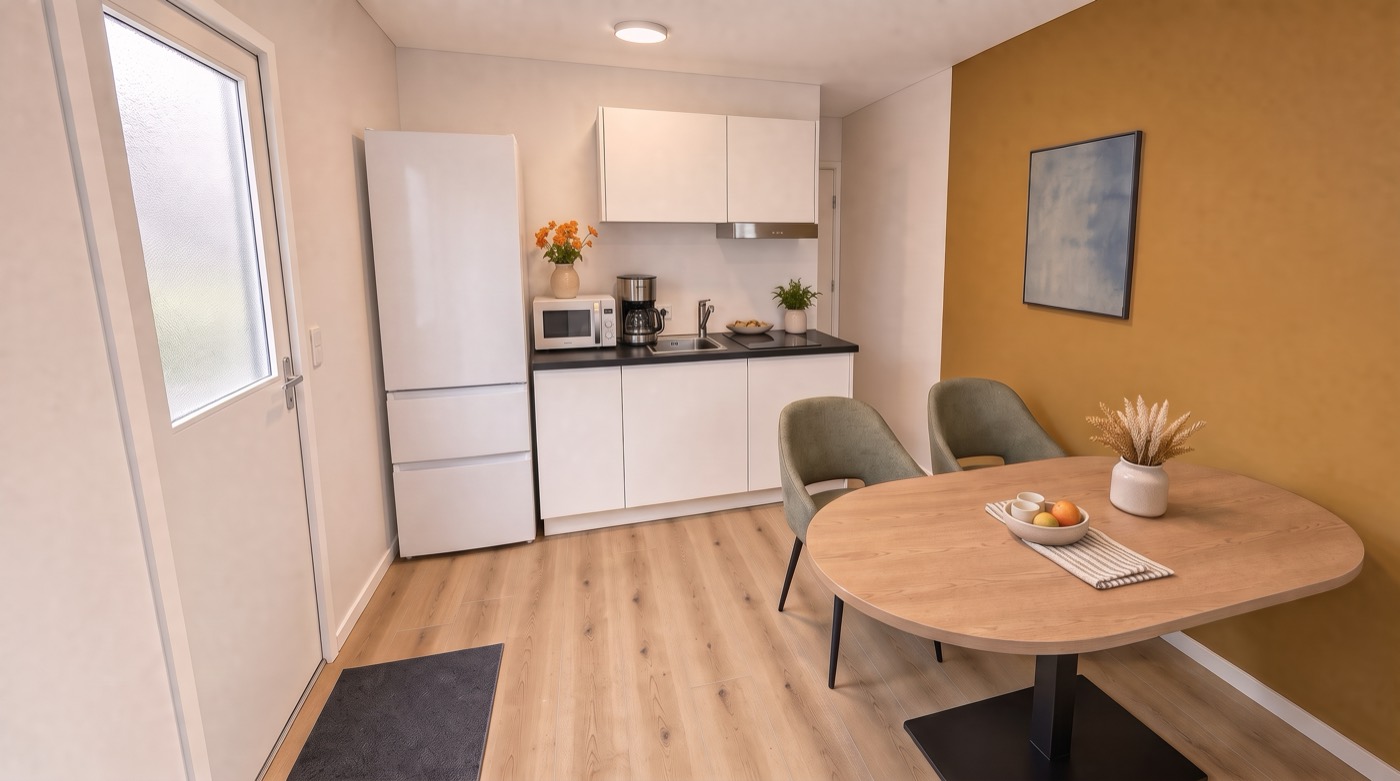 De keuken met koel-vriescombinatie, magnetron en koffiezetapparaat, en de eettafel met twee stoelen.