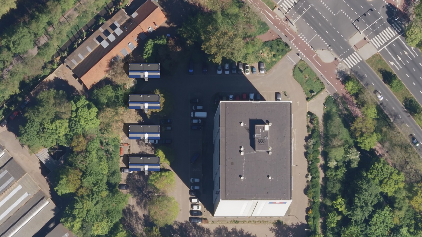 Luchtfoto van de Vierkant-flat met de acht logeerwoningen ingetekend op de parkeerplaats aan de westzijde.